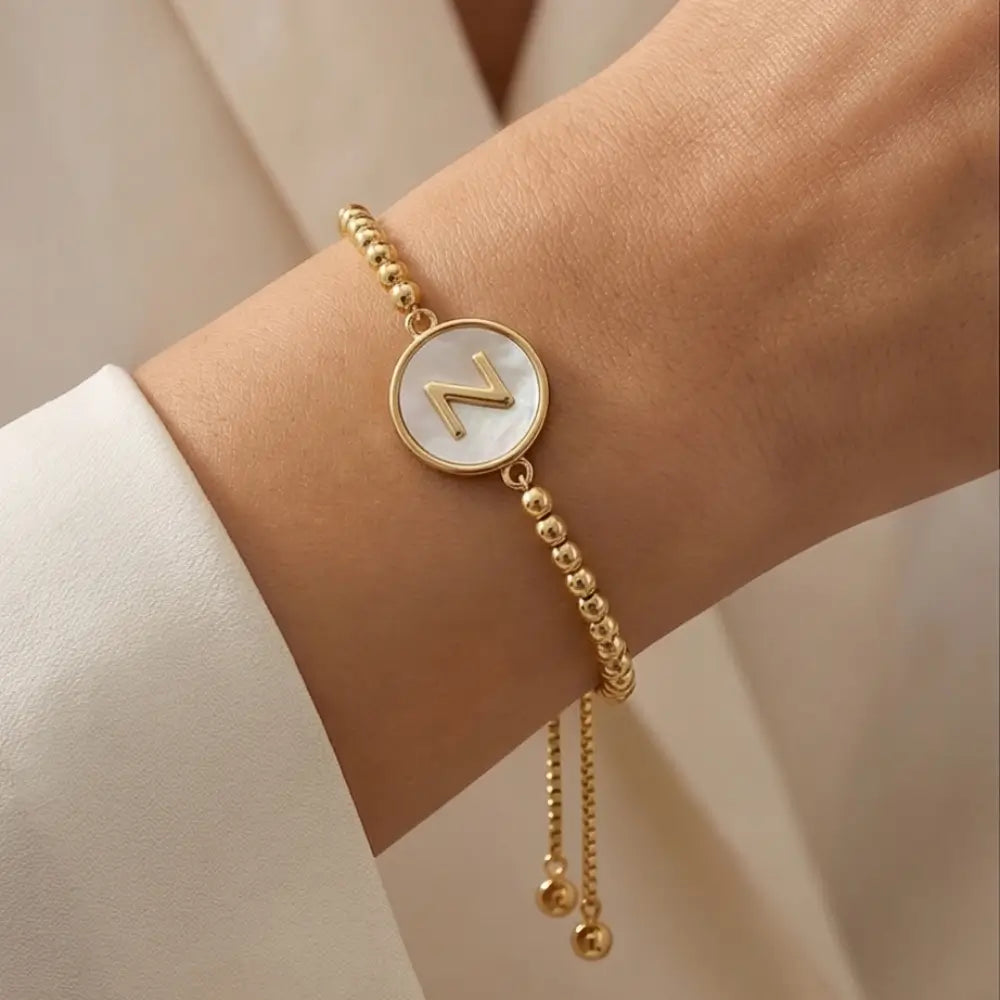 Gold bracelet with a circular charm featuring the letter 'Z' on a neutral background